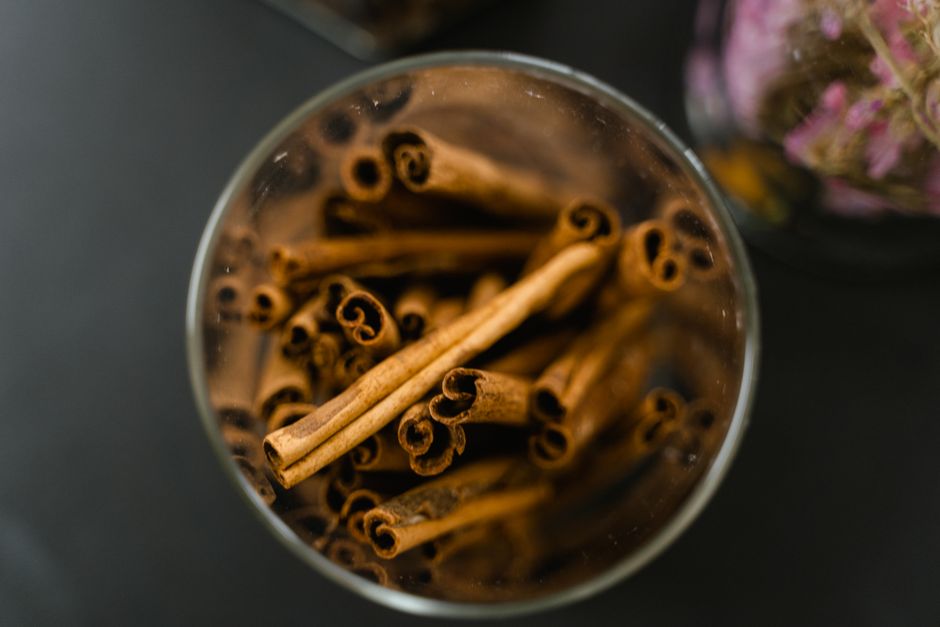 Palitos de canela aromáticos en un frasco de vidrio sobre superficie negra