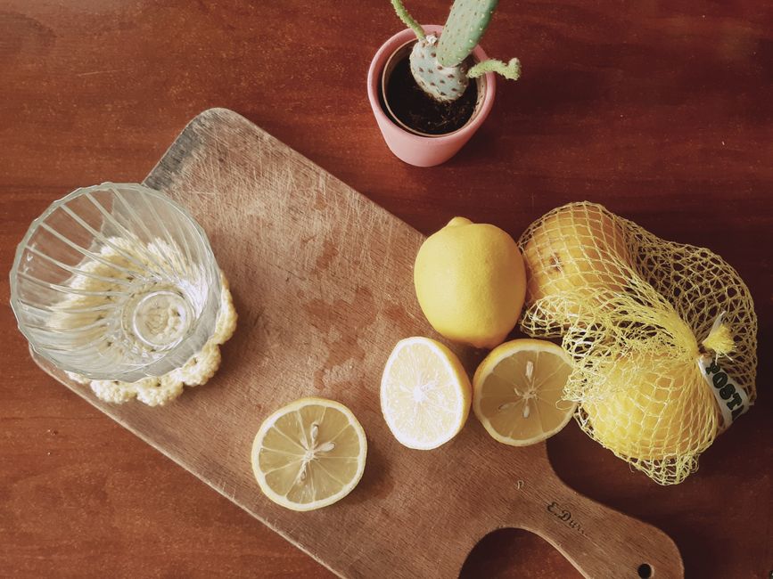 Limones frescos sobre tabla de madera con un vaso y un cactus