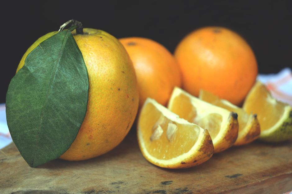 Naranjas maduras y rebanadas en una tabla de madera
